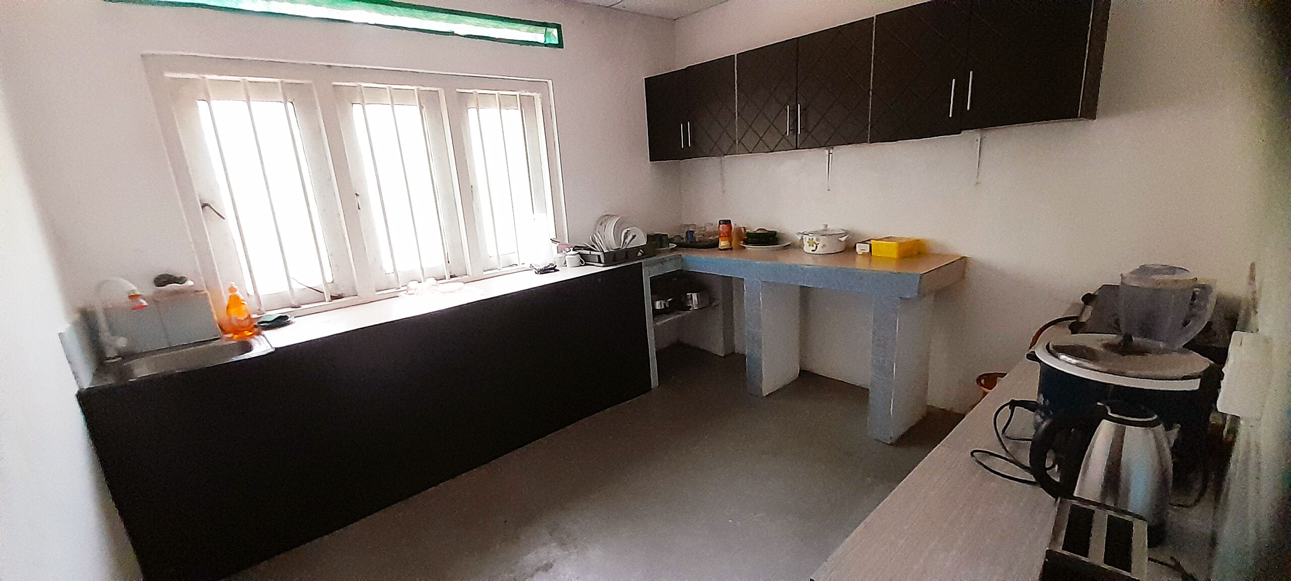 A kitchen with a black countertop, a window with blinds, and a stove.