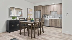 A modern kitchen with wooden cabinets, a built-in oven, and a stainless steel refrigerator.