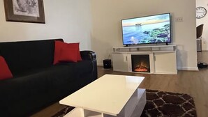 A living room with a sofa, a flat-screen TV, a fireplace, and a coffee table.