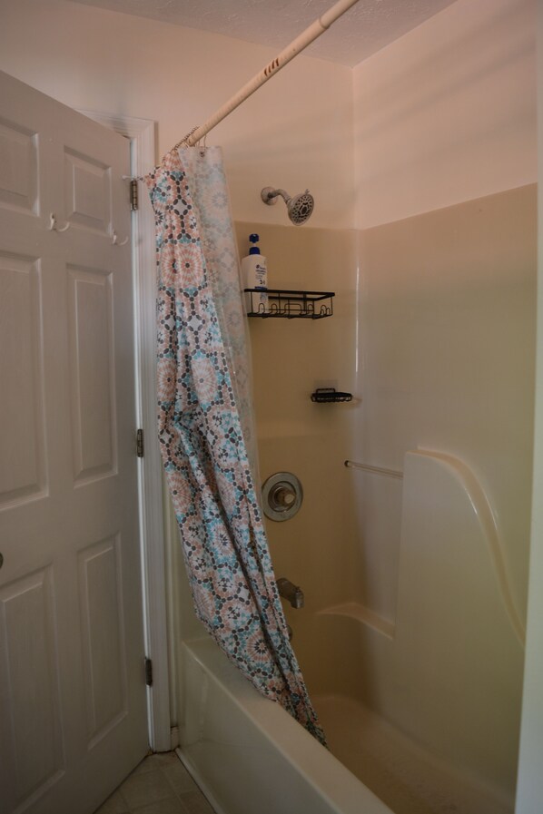 A shower area with a shower curtain, a showerhead, and a soap dispenser on a shelf. - Poconos Summer Getaway: Family, Games & Memories! (Pocono Summit)