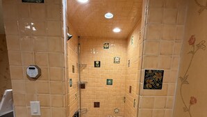 Kylpyhuone, jossa on laatoitetut seinät, suihku, wc ja pesuallas.