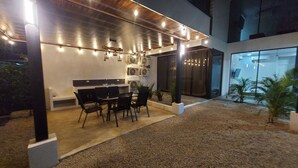 An outdoor dining area with a modern design, featuring a table and chairs, surrounded by a low wall and a gravel path. - Amazing 3-bedroom apartment with AC in Tamarindo (Tamarindo)