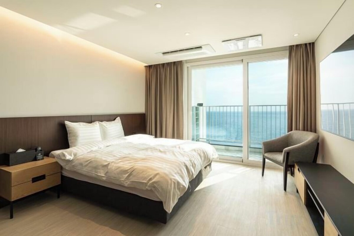 Een moderne hotelkamer met een groot bed, een bureau en uitzicht op zee.