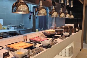 Un buffet proposant divers plats et ustensiles, un évier et un éclairage au plafond.