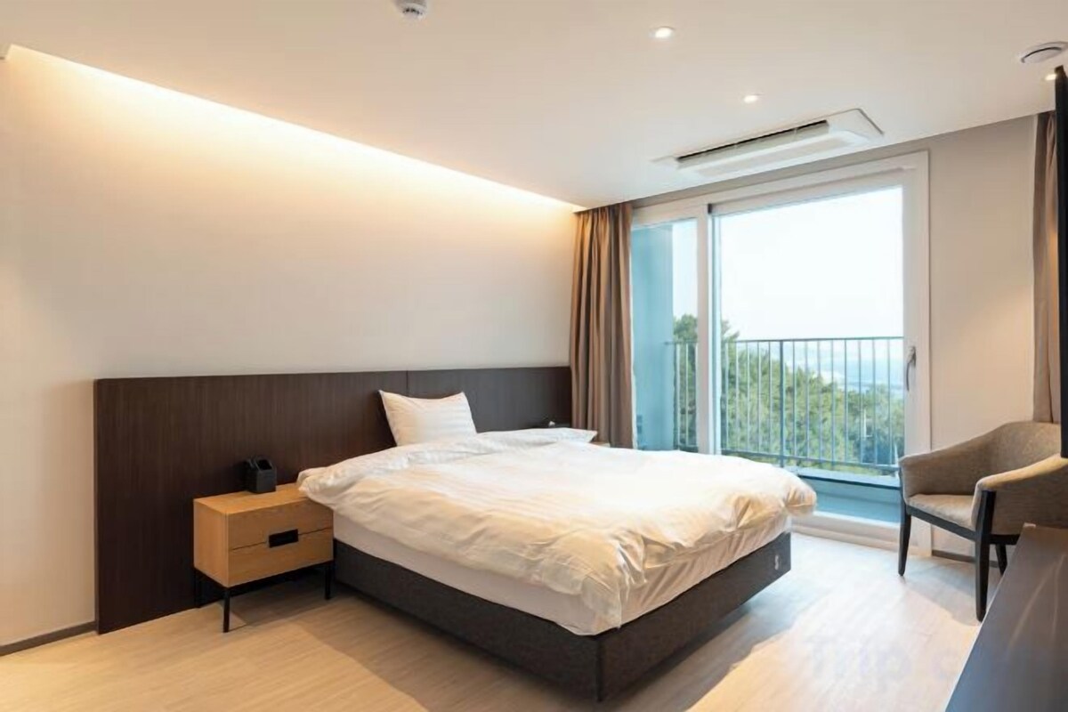 Een moderne hotelkamer met een groot bed, een nachtkastje, een stoel en een balkon met uitzicht.