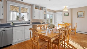 Una cocina con armarios blancos, una mesa de comedor de madera y sillas.