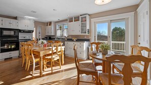 Una cocina amplia con armarios blancos, una mesa de comedor de madera y un ventanal con vistas al exterior.