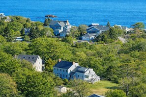 A coastal residential area with houses surrounded by lush greenery and a view of the ocean. - Bell View: Private tennis court and an in-law (Gloucester)