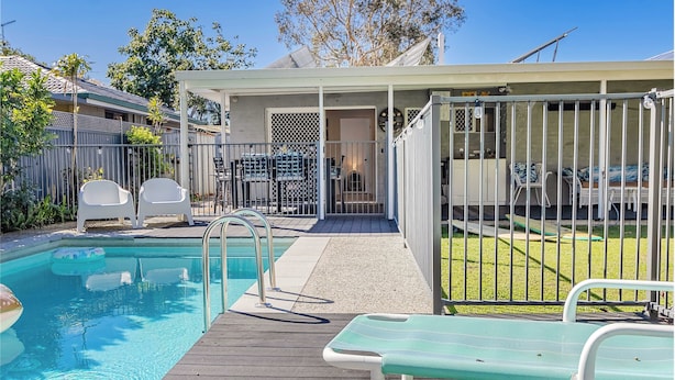 A pool area with a wooden deck, lounge chairs, and a fenced patio. - Slow M Ocean Cabarita - Pet Friendly (Bogangar)