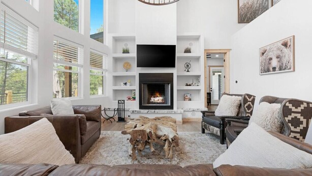 A spacious living room with a fireplace, leather sofas, and a rustic wood table. - Charming & Luxurious 5-Bedroom Cabin in Heber (Overgaard)