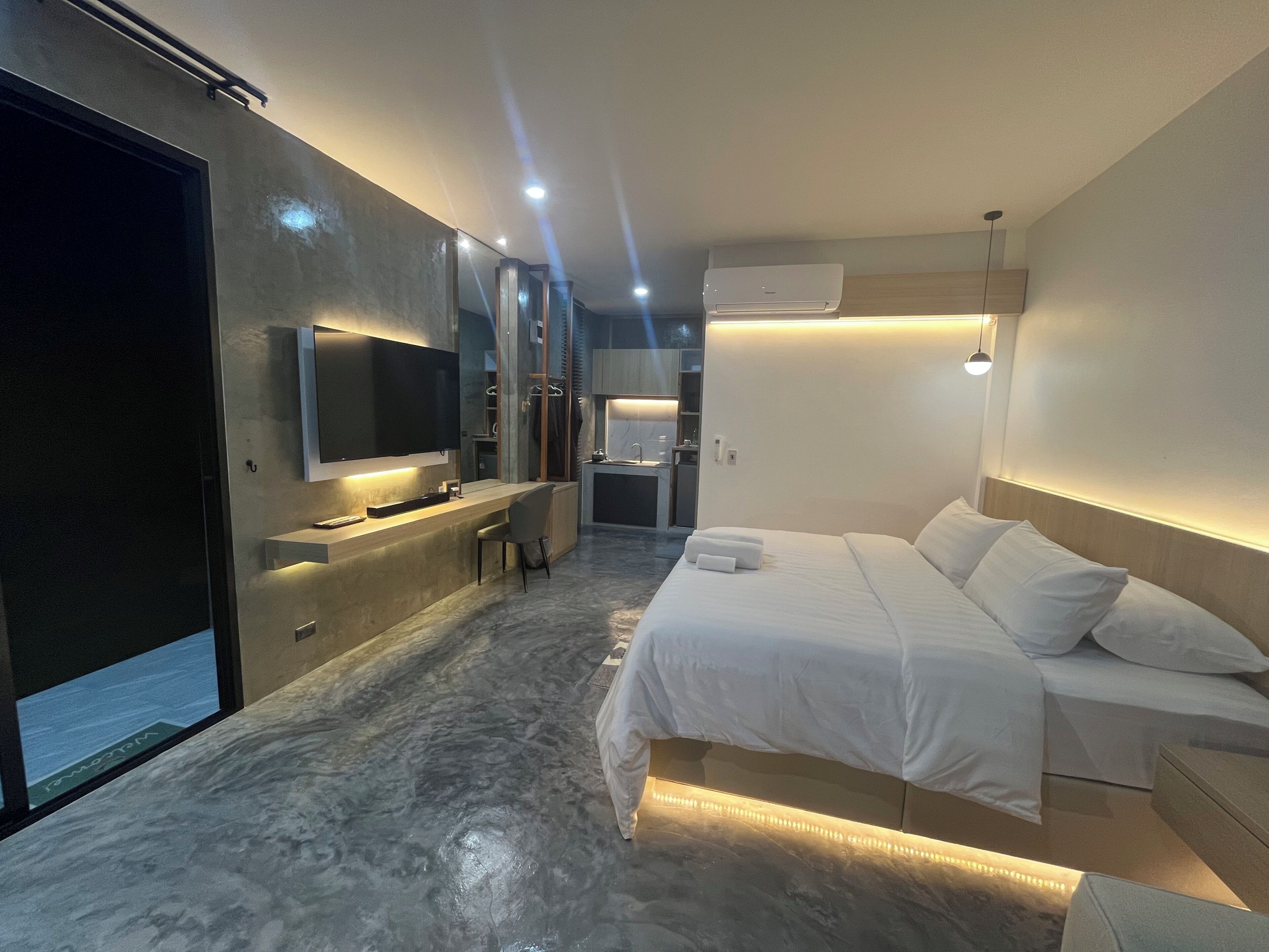 Una habitación de hotel moderna con cama, escritorio, televisor y aire acondicionado.