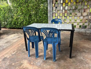 Una mesa con cuatro sillas de plástico azul, una pata negra y una superficie de vidrio.