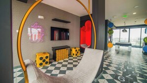 Een moderne lounge met een hangmat, een neonbord, een open haard en een zwart-wit geruite vloer.