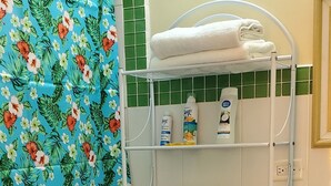 Ein Badezimmer mit Toilette, einem Ablagefach für Pflegeprodukte, einer Duschvorhang und einem roten Teppich.