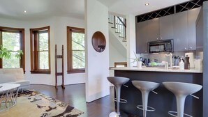 Une cuisine moderne équipée d’un four à micro-ondes, de tabourets de bar et d’un escalier.