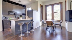 Une cuisine moderne dotée d’un îlot central, de tabourets de bar et d’un coin repas avec une table et des chaises.