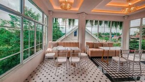 A spacious room with large windows, a checkered floor, and a central seating area with a table and chairs. - Koyad resort (Nakhon Si Thammarat)