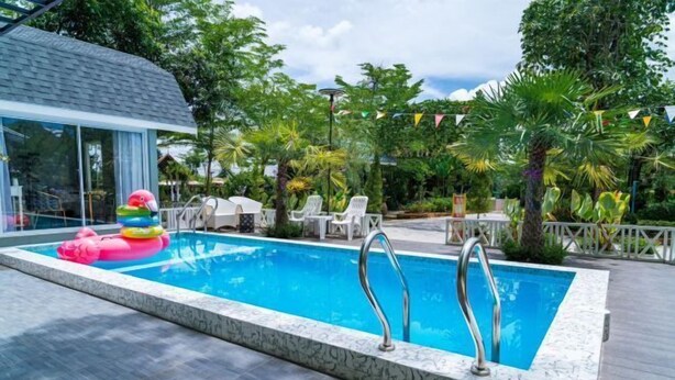 A swimming pool with a glass enclosure, lounge chairs, and a deck.