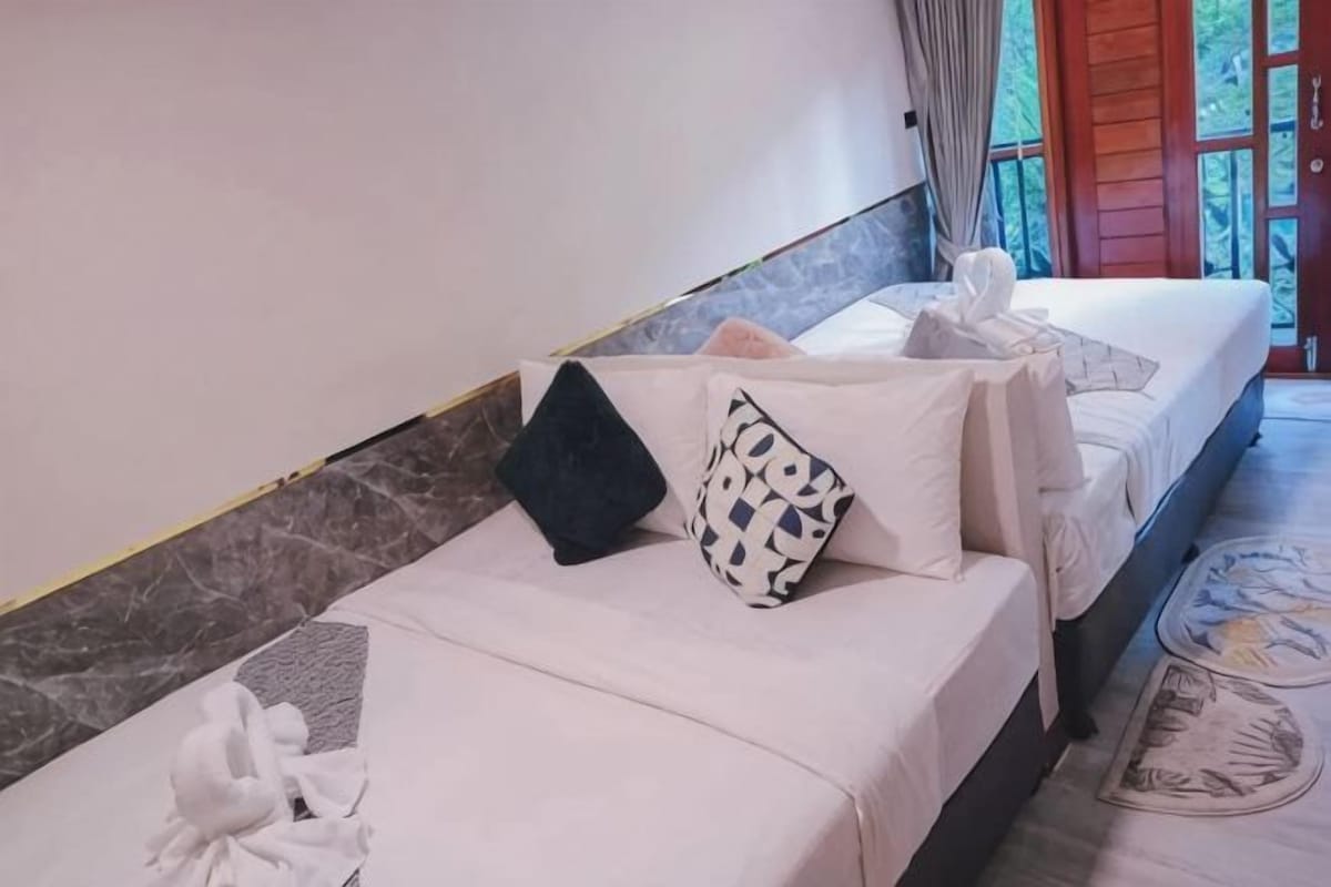 Ein Hotelzimmer mit zwei Betten, einer Marmorwand und Blick ins Freie.