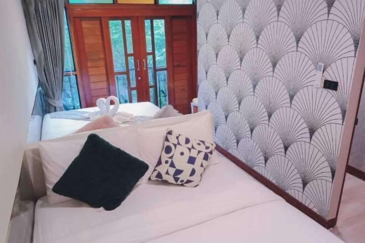 A bedroom with a bed, two pillows, a wooden door, and a patterned wall.
