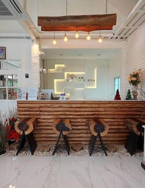 Una zona de recepción con mostrador de madera, una lámpara moderna y un cartel con caracteres chinos.