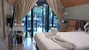 A hotel room with a large bed, a TV mounted on the wall, and a balcony with outdoor seating. - Koyad resort (Nakhon Si Thammarat)