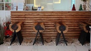 A reception desk with a modern design, featuring a wooden backdrop and a logo. - Koyad resort (Nakhon Si Thammarat)