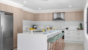 Une cuisine moderne dotée d’un îlot central, d’appareils électroménagers en acier inoxydable et de meubles de rangement en bois clair.