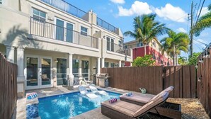 A two-story house with a swimming pool, outdoor furniture, and a wooden fence.
