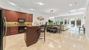 A spacious kitchen with granite countertops, dark wooden cabinets, and a central island.