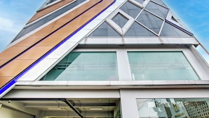 Un bâtiment moderne à la façade géométrique, doté de grandes fenêtres et d’une entrée imposante.