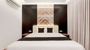 Une chambre d’hôtel moderne avec un grand lit, une tête de lit ornée d’un motif géométrique et un climatiseur fixé au mur.