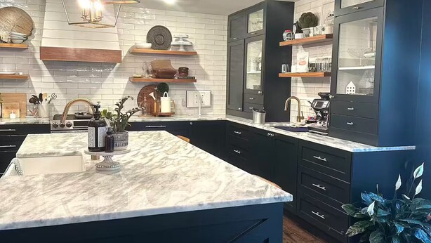 A modern kitchen with a marble island, black cabinetry, and a unique geometric chandelier.