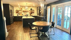 A modern kitchen with a central island, black cabinets, and a dining area with a round table and chairs.