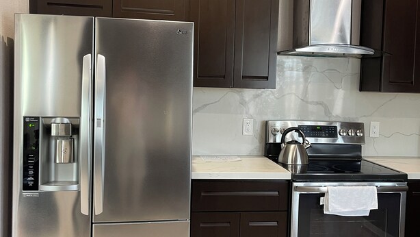 Eine moderne Küche mit Edelstahlgeräten, darunter ein Kühlschrank, eine Kaffeemaschine und ein Backofen.