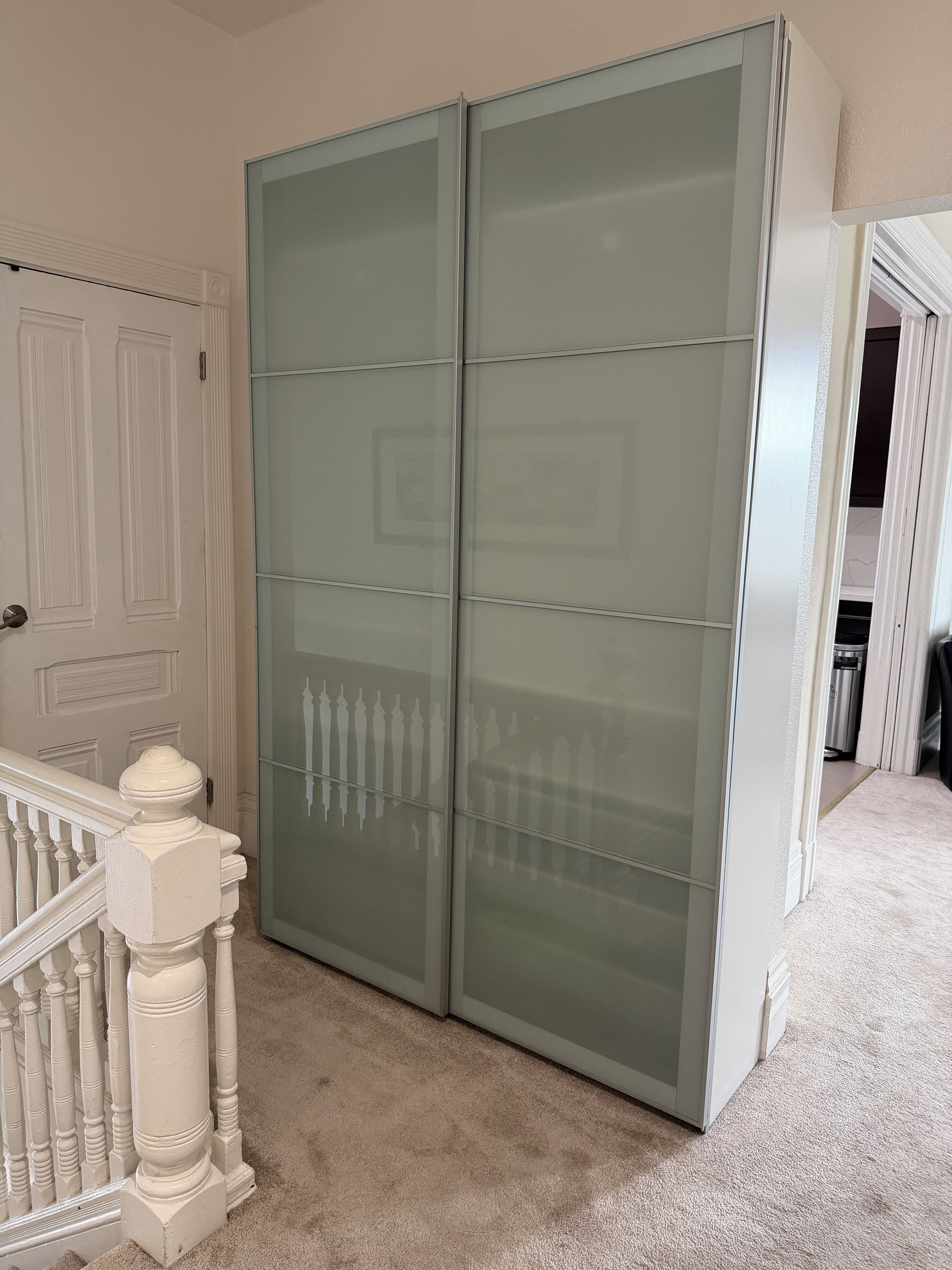 A room with a large sliding glass door closet, a white door with paneling, and a carpeted floor.