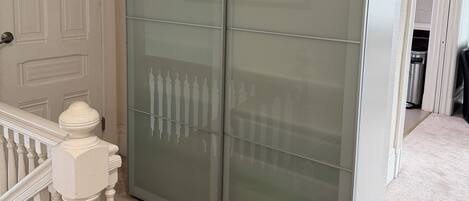 A room with a large sliding glass door closet, a white door with paneling, and a carpeted floor.
