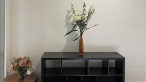 Eine schwarze Konsole mit einer Vase voller weißer Blumen vor einer schlichten Wand.