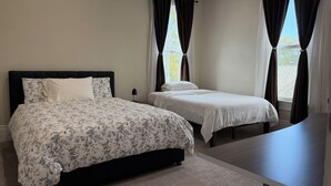 Una camera da letto con due letti, una scrivania e una finestra con tende.