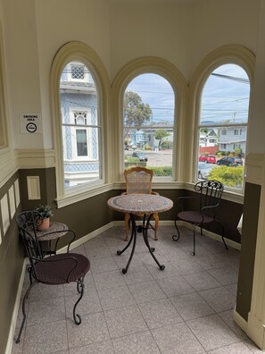 A corner room with three arched windows, a round table, and two chairs. - Alameda Modern Victorian 4BD unit A (Alameda)
