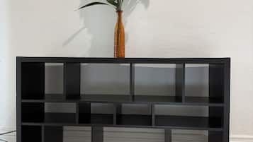 Una consola negra con un jarrón de flores blancas frente a una pared blanca.
