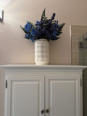 A white cabinet with a decorative vase containing blue flowers on top. - Alameda Modern Victorian 4BD unit A (Alameda)