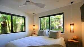 A modern bedroom with a large bed, two bedside tables, and a ceiling fan. - Byron Oakland Oasis (Byron Bay)