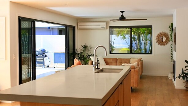 A modern kitchen with a large island, a built-in sink, and a ceiling fan. - Byron Oakland Oasis (Byron Bay)