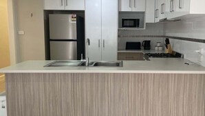 Une cuisine moderne dotée d’un îlot central, d’appareils électroménagers en acier inoxydable et de meubles de rangement en bois clair.