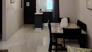 Un espace de salle à manger moderne avec une table centrale, des chaises noires et un lustre.