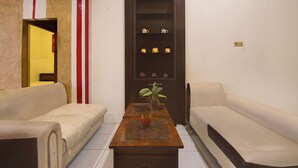 A living room with a sofa, a coffee table, and a shelf with decorative items. - Hotel O Makassar near RS Grestelina formerly Wisma Makassar (Makassar)