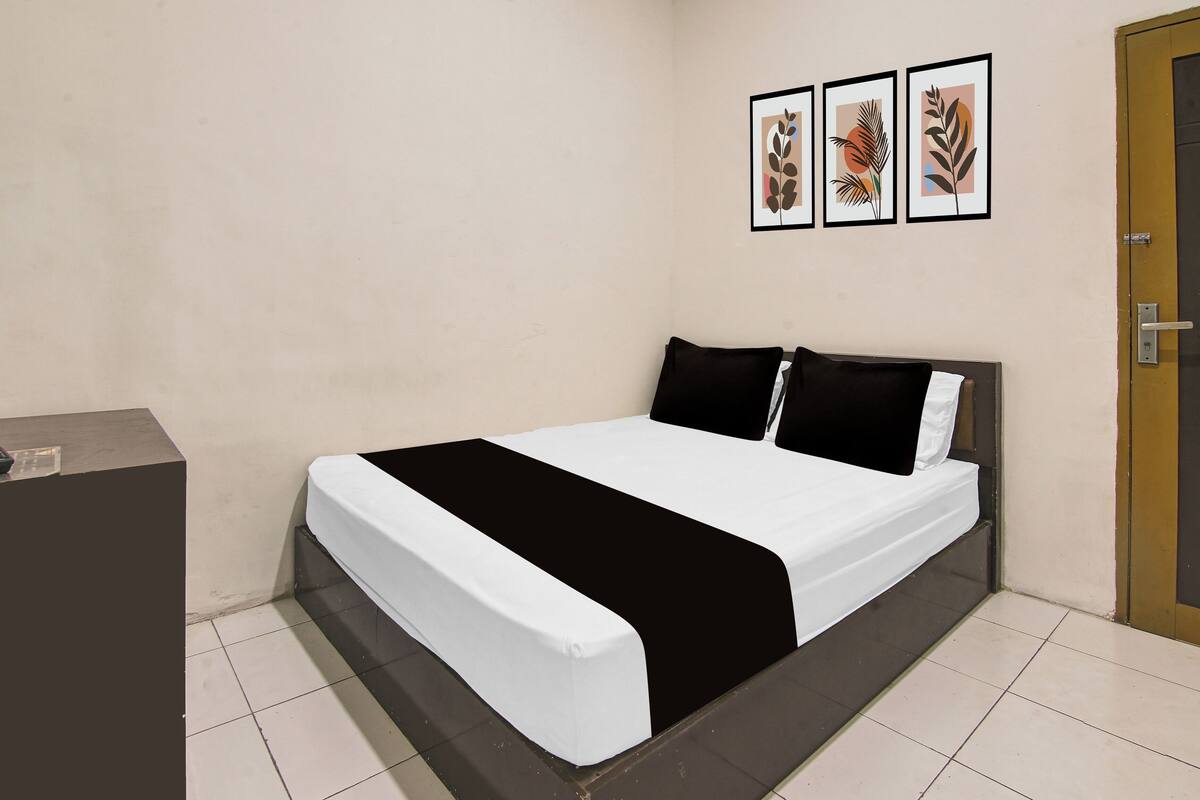 Un dormitorio con una cama, un escritorio y tres cuadros en la pared.