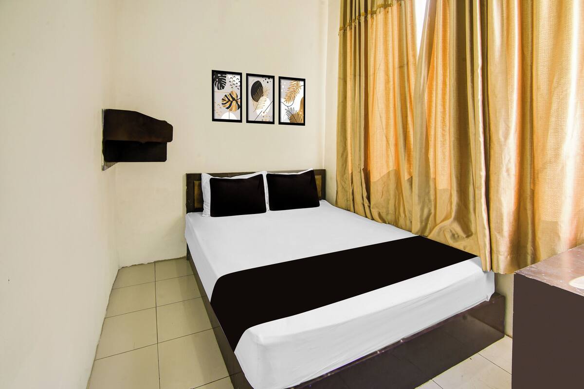 Una habitación de hotel con una cama, un estante en la pared y tres cuadros enmarcados.