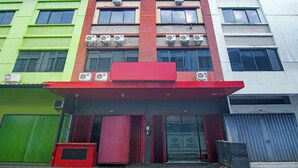 A multi-story building with air conditioning units, a red awning, and a green door. - Hotel O Makassar near RS Grestelina formerly Wisma Makassar (Makassar)